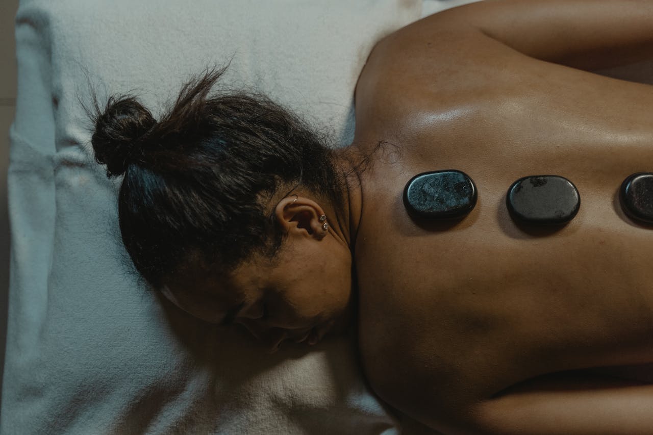 A woman enjoys a relaxing spa treatment with hot stones on her back for therapeutic relief.